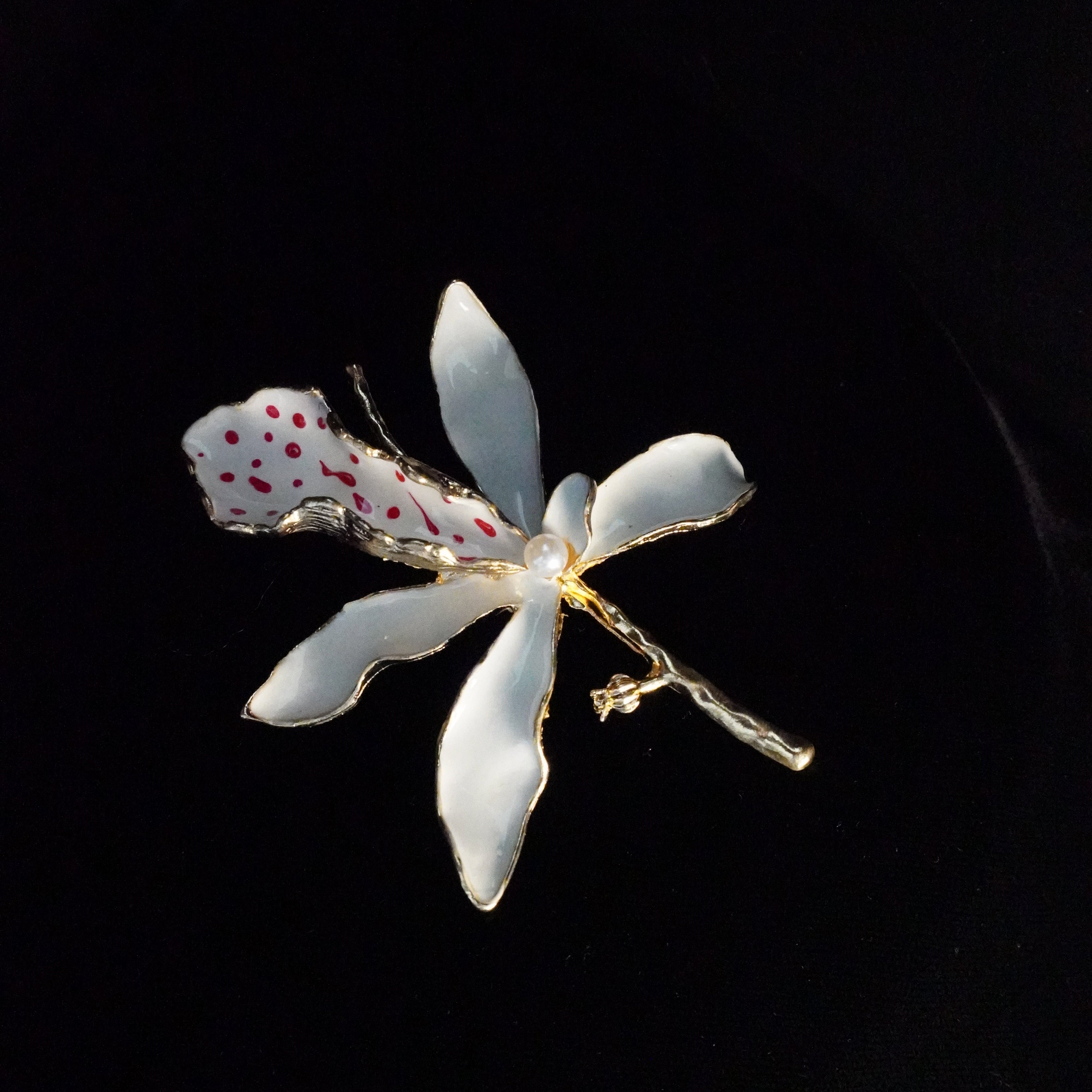 White orchid-shaped hairpin with red accents on a black background